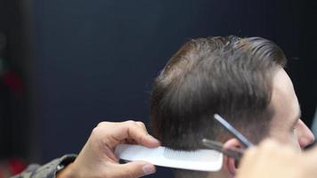 Barber trims back of head hair of client with comb and scissors video