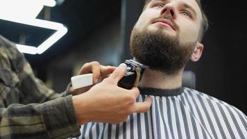 Barber trims man's face and neck hair with comb and clippers video