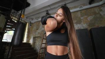 Frau mit langen dunklen Haaren und schwarzem Sport-BH löst Boxhandschuh mit Zähnen video