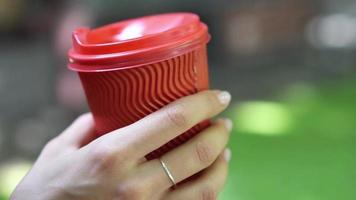 Close up on a red cup of coffee held by a brunette woman talking video