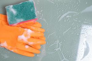 guantes con una esponja húmeda para limpiar vidrio cubierto con espuma. foto