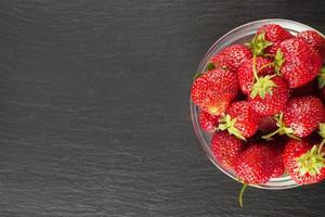 Strawberry in a bowl on black slate backround. top view, flat lay with copy space for text photo