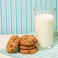 Tasty cookies and glass of milk on blue background photo