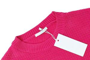 White blank rectangular clothing tag on pink knitted sweater isolated on white background photo