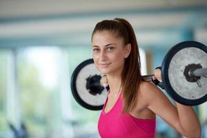 young woman in fitness gym lifting  weights photo