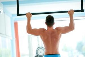 apuesto joven trabajando en el gimnasio foto