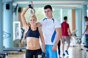 joven mujer deportiva con entrenador ejercicio levantamiento de pesas foto