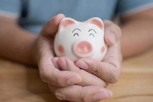 Hands holding piggy bank. Saving concept with piggy bank indoor photo