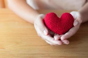 Adult hands holding a yarn red heart photo