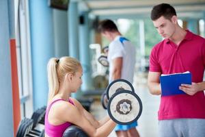 joven mujer deportiva con entrenador ejercicio levantamiento de pesas foto