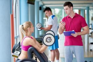 joven mujer deportiva con entrenador ejercicio levantamiento de pesas foto