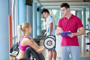 joven mujer deportiva con entrenador ejercicio levantamiento de pesas foto