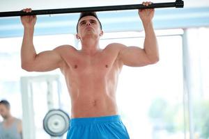 apuesto joven trabajando en el gimnasio foto