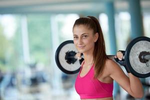 young woman in fitness gym lifting  weights photo