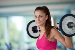 young woman in fitness gym lifting  weights photo