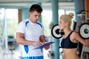 joven mujer deportiva con entrenador ejercicio levantamiento de pesas foto