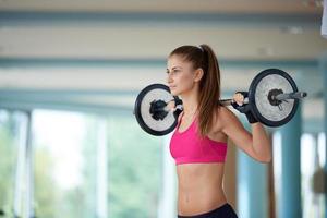 young woman in fitness gym lifting  weights photo