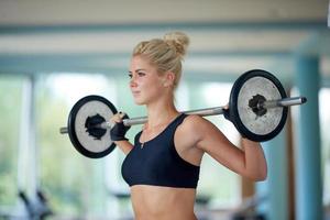 young woman in fitness gym lifting  weights photo