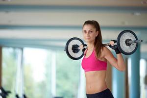 young woman in fitness gym lifting  weights photo