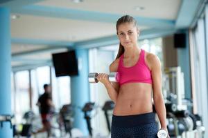 lifting some weights and working on her biceps in a gym photo