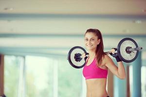 young woman in fitness gym lifting  weights photo