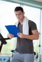 entrenador con portapapeles de pie en un gimnasio brillante foto