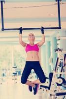 young woman in fitness gym lifting on bar photo