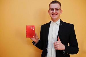 Young handsome man holding Swiss Confederation passport id over yellow background, happy and show thumb up. Travel to Europe country concept. photo