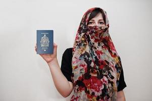una joven musulmana árabe vestida con hiyab tiene pasaporte de canadá con fondo de pared blanca, retrato de estudio. foto