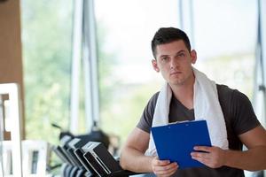 entrenador con portapapeles de pie en un gimnasio brillante foto