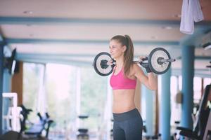 young woman in fitness gym lifting  weights photo