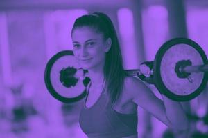mujer joven en el gimnasio levantando pesas foto
