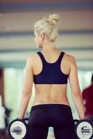 lifting some weights and working on her biceps in a gym photo