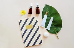 Flat lay of various organic skincare and beauty products for mock up with flower and notebook in minimal style photo