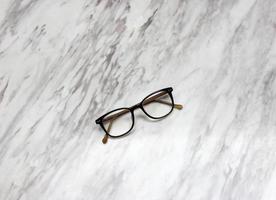 Eyeglasses on black and white marble table texture photo