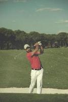 golfista golpeando un tiro de búnker de arena foto