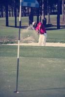 golfer hitting a sand bunker shot photo