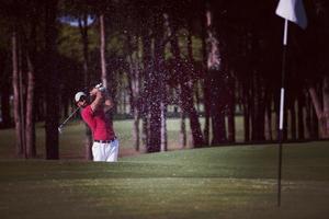 golfista golpeando un tiro de búnker de arena foto