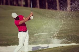 golfista golpeando un tiro de búnker de arena foto