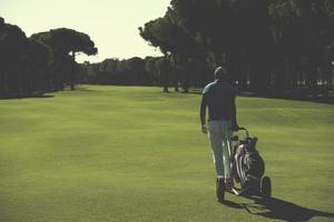 jugador de golf caminando con bolsa de ruedas foto