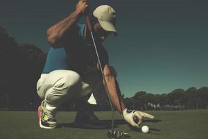 mano del hombre poniendo una pelota de golf en el agujero foto