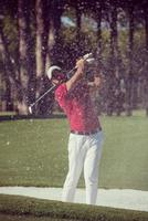 golfer hitting a sand bunker shot photo