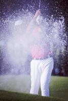 golfer hitting a sand bunker shot photo