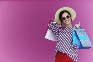 mujer joven con bolsas de compras sobre fondo rosa foto