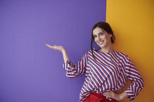 Portrait of happy smiling young beautiful woman in a presenting gesture with open palm photo