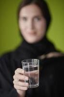 Middle eastern woman in abaya holding a glass of water photo