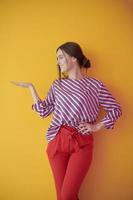 Portrait of happy smiling young beautiful woman in a presenting gesture with open palm photo