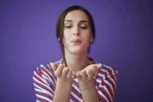 Close up portrait of charrming girl  blowing air kiss from open palm photo