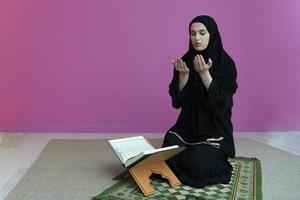 Middle eastern woman praying and reading the holy Quran photo