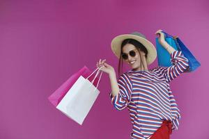 Young woman with shopping bags on pink background photo